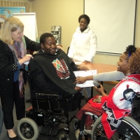 <p>
	Sipho Innocent Nkosi is being given a DRPI T-shirt from Marcia Rioux, while Bongiwe Malope is handing over the certificate. Someone looks on in the background.</p>
