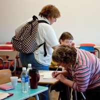 <p>
	Mary Anthony is bending down to fill out interview forms on a desk.</p>
