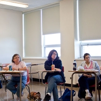 Monitors seated abreast in small desks during training.