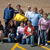 A outdoor group shot of the seminar participants, who are posed against a yellow brick wall.