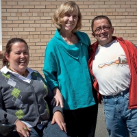 Susan Ralph, Marcia Rioux and Steve Estey pose outside with a yellow brick building in the background.