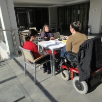 Seated outside at  a table in the sun light practicing during the country monitoring training in Montenegro. 