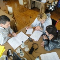 Pictured sitting around a table are three participants practicing individual monitoring techniques. The photo is taken from above. 
