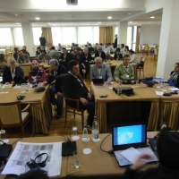 A photo of the training room, taken from the front of the room looking towards the back everyone is seated and listening to the presentation. 