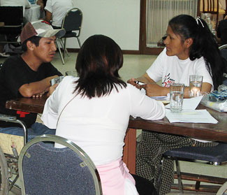 Three training participants (1 male and 2 female) are sit at a table to practice their interviewing skills.