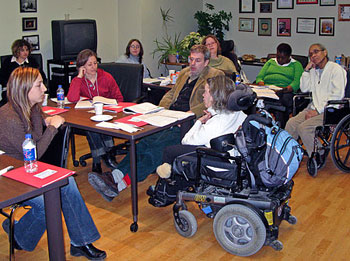 Training participants sit around tables looking at training materials