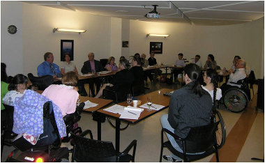Participants at the consultation meeting are shown at the tables in the room