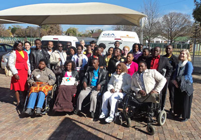A photo of all participants and facilitators sitting and standing in three rows.  It is taken outside, in the parking lot of the National Council for Persons with Physical Disabilities in South Africa. 