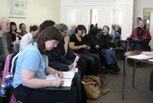 Participants sit while listening and taking notes during training